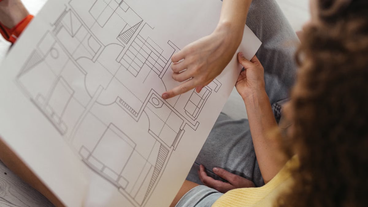 Two people reviewing and discussing a detailed architectural floor plan.